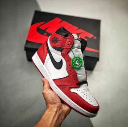 Red and white sneaker with black Nike logo held in a hand, displayed on a gray surface.